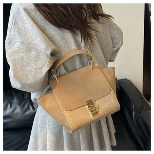 Close-up of khaki satchel with matte leather and crocodile pattern in a home setting