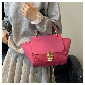 Detail view of fuchsia winged handbag with matte suede flap and crocodile texture