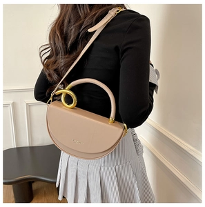 Rear view of model wearing a khaki semi-circular leather handbag with gold metal rings
