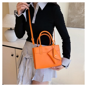 Detail of bright orange PU leather handbag with detachable strap and small coin purse