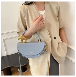 Detail of light blue crescent leather bag with gold twist handle and shoulder strap