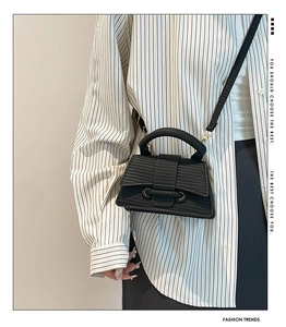 Detail of black woven textured mini tote bag with gold hardware and slim shoulder strap