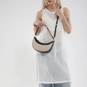 Minimalist straw crescent crossbody bag with black leather trim and woven texture