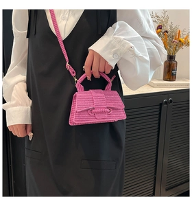 Detail of pink woven mini handbag featuring intricate craftsmanship and a round loop clasp