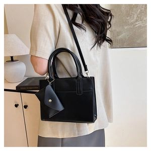 Détail du sac cabas noir avec pendentif enveloppe et gaufrage en cuir tendance
