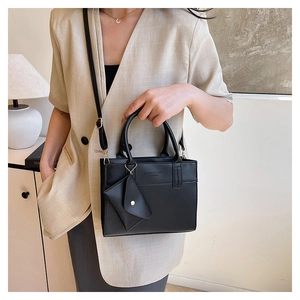 Détail du sac à main en cuir noir porté par un mannequin avec un blazer beige chic