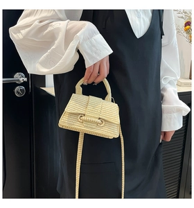 Detailed view of beige woven straw handbag with handle and adjustable shoulder strap