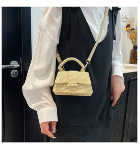 Detail of beige woven tote bag featuring a trapezoidal flap and unique circular buckle design