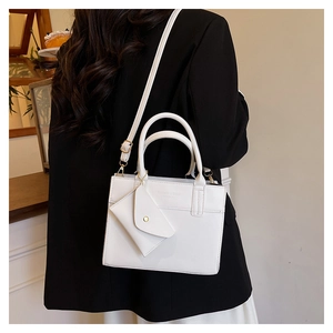 Detail of white PU leather handbag with embossed text, top handle and detachable small pouch