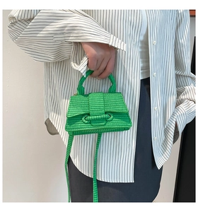 Model wearing a green woven mini square bag with crossbody strap and top handle