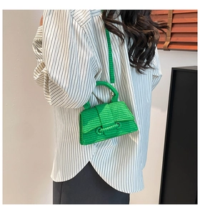 Close-up of a vibrant green woven handbag with curved base and braided circular handle