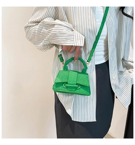 Close-up of bright green woven mini handbag with detachable shoulder strap and handle