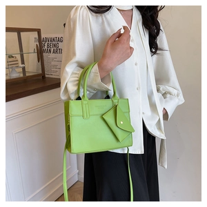 Détail du sac à main vert vif avec pochette enveloppe amovible sur une table en bois