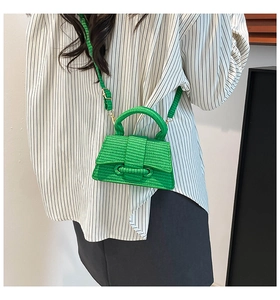 Detail of green woven hourglass mini handbag featuring a sleek top handle and crossbody strap