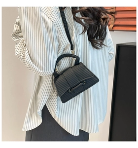 Detail of black hourglass handbag with woven texture shown on a model