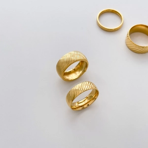 Close-up of 18K gold plated titanium rings featuring textured diagonal hammered patterns