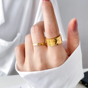 Detail of wide and thin gold hammered rings showing textured finish on a finger