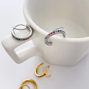 Gros plan de boucles d'oreilles huggie arc-en-ciel avec zircons colorés sur céramique