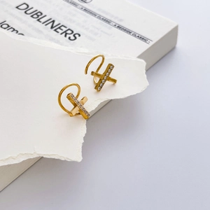 Détail des boucles d'oreilles en X plaquées or avec zircons et design croisé géométrique