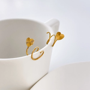 Détail macro de boucles d'oreilles spirales en or 18K avec motifs de cœur rayonnant