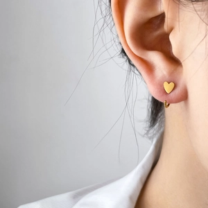 Gros plan de puces d'oreilles cœur et petits anneaux dorés avec placage en or 18 carats