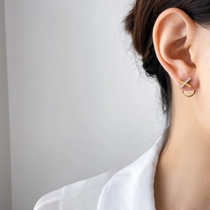 Gros plan de boucles d'oreilles en X plaquées or 18K avec cristaux sur mannequin