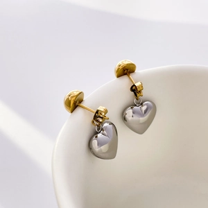 Détail de boucles d'oreilles cœur bicolores avec créole dorée et pendentif cœur argenté