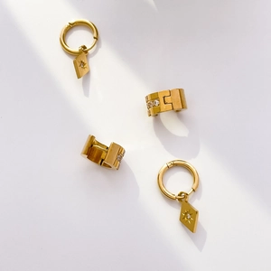 Détails des boucles d'oreilles losange dorées et anneaux larges avec sertissage de diamants
