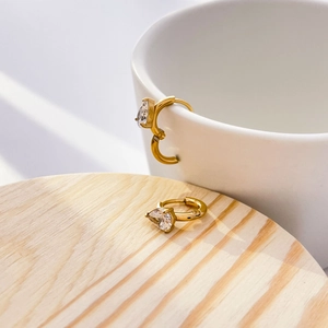 Vue détaillée de boucles d'oreilles dorées avec zircon goutte sur tasse en céramique