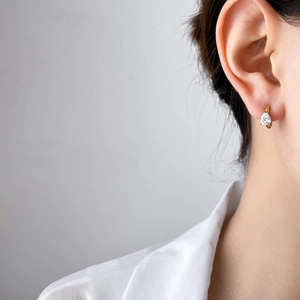 Détail d'une boucle d'oreille en zircone poire dorée portée par un mannequin