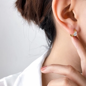 Créole dorée avec pendentif en zircon en forme de goutte, portée par un mannequin