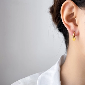 Gros plan de boucles d'oreilles créoles coeur dorées minimalistes sur un modèle