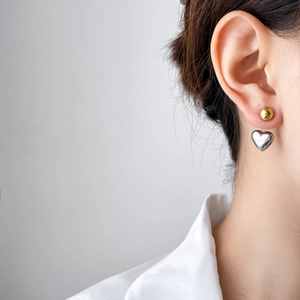 Boucles d'oreilles cœur bicolores avec sphère dorée et pendentif argenté sur mannequin