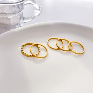 Set di cinque anelli in acciaio al titanio placcato oro 18K con motivi geometrici materici