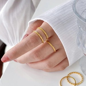 Dettaglio di sottili anelli in acciaio al titanio placcati oro 18K con incisioni geometriche