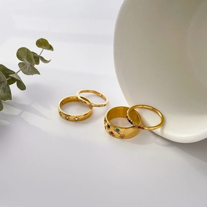 Detailed view of four gold ring set featuring star engravings and colorful zircons
