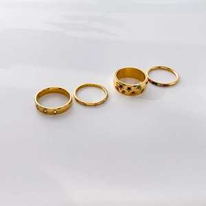 Detail of four gold-plated rings featuring rainbow stones, star motifs and textured bands