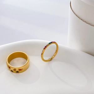 Close-up of gold rings with rainbow gems and star motifs on white ceramic tray