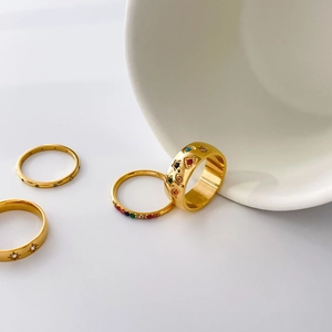 Detail of gold rings set with colorful gems, hollow stars, and moon patterns in boho style