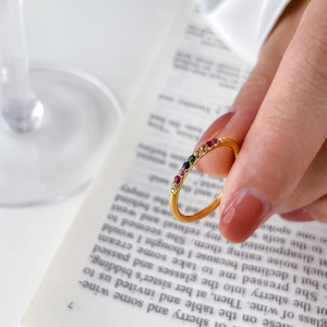 Detailed shot of gold ring with rainbow gemstones held over a vintage book background