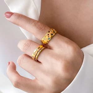 Gold ring set with colorful stones and star carvings shown on model's hand