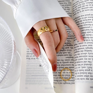 Set of three golden rings with rainbow crystals and wide band on a book surface
