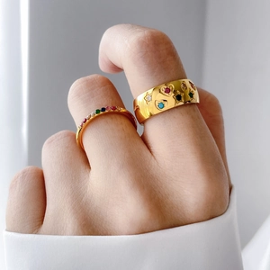 Close-up of gold hollow constellation rings with colorful gemstones on a hand
