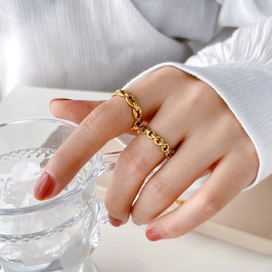 Gros plan d'une bague chaîne creuse dorée portée à la main au style luxe raffiné