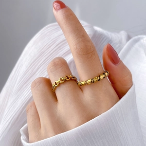 Vue détaillée de la bague chaîne dorée et de la bague torsadée avec manucure rouge