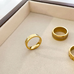 Macro detail of three gold titanium rings featuring hammered and tree bark textures