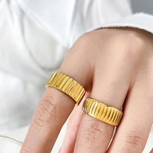 Detail of 18K gold pleated gear ring with bark texture on model's fingers