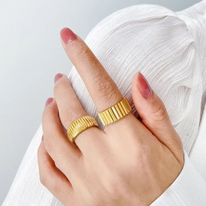 Detail of 18K gold pleated texture rings with wide bark-inspired patterns on hands