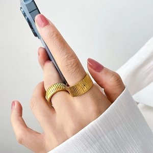 Detail of 18K gold titanium gear rings with vertical textured bark design on model hand