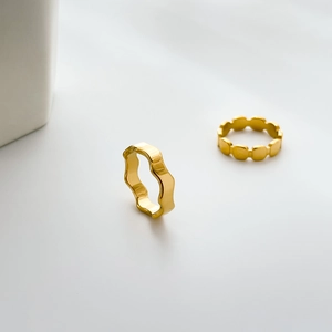 Detail of 18K gold plated titanium steel rings with wave and geometric textures